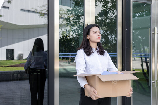 A young Chinese female employee in the workplace concept of resignation shows a tired expression
