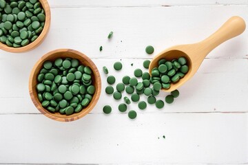 Organic spirulina in wooden bowls and on a white wooden background. Concept of healthy lifestyle choices and natural supplements
