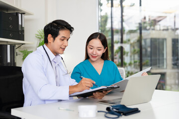 Obraz premium Doctor working on laptop talking to nurse about healthcare update medical record. Professional and consultation with professional for diagnosis, test results or checkup in hospital.