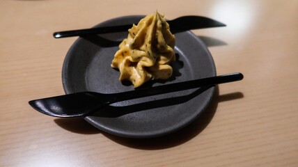 close up of a creamy golden colour spread or butter in swirl cream shape with two black knife on the side