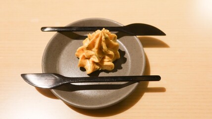 close up of a creamy golden colour spread or butter in swirl cream shape with two black knife on the side