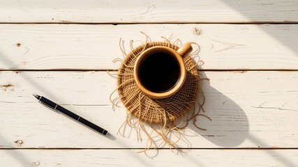 Morning refreshment and reflection A cup of dark liquid and a pen on a sunlit white wood surface