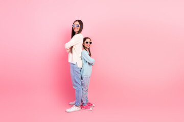 Joyful mother and daughter enjoying casual bonding time on a pink background in vibrant casual wear...