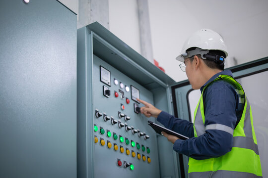 Engineer performs inspection on load center unit, carefully checking control panel and recording data on tablet to ensure proper operation and safety compliance