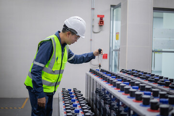 Technician inspects backup battery system carefully in power facility ensuring safety and...