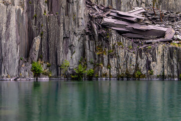 Dramatic Layers of Rock and Industrial Remnants Above Clear Water