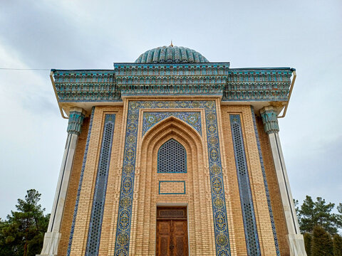 The historical Mausoleum of Abu Mansur al-Maturidi in Samarkand features intricate blue and gold mosaic tilework and a ribbed turquoise dome defining significant Central Asian religious architecture