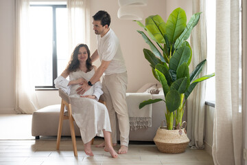 Happy couple cherishing their pregnancy journey, enjoying cozy moments together in their living room while preparing for parenthood