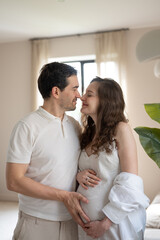 Happy pregnant couple touching belly and sharing a tender moment at home, enjoying their pregnancy
