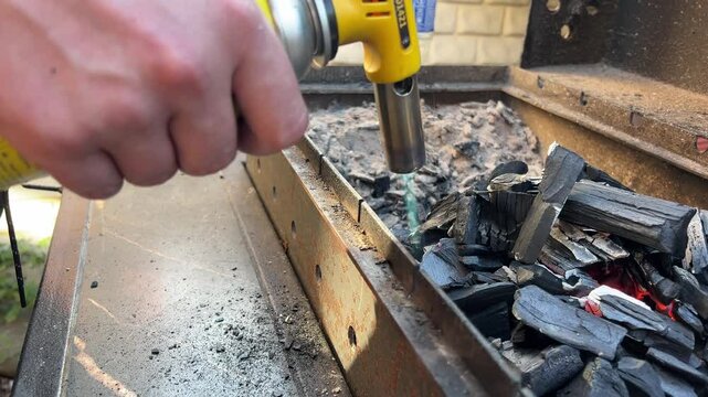 Man's hands stirring coals for cooking outdoors