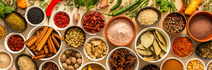 Collection of assorted spices and herbs spread on a beige background, blending exotic aromas and colors to inspire flavorful cooking, banner