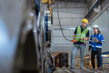 Workers inspect machinery in a warehouse during daylight hours