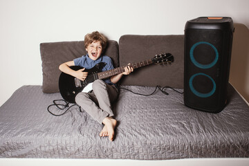  Young boy playing electric guitar at home, learning music and practicing concentration. The child appears focused and relaxed, suggesting a music practice or learning moment. Play music at home. 