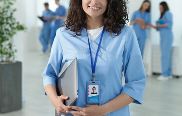 Medical student in uniform with laptop indoors, selective focus