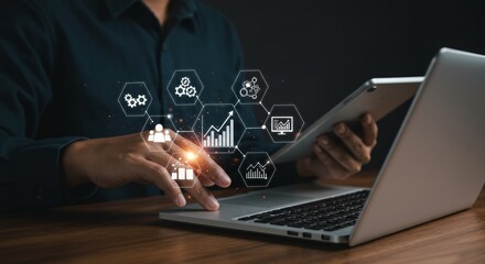 Person using laptop and tablet with digital interface of business icons