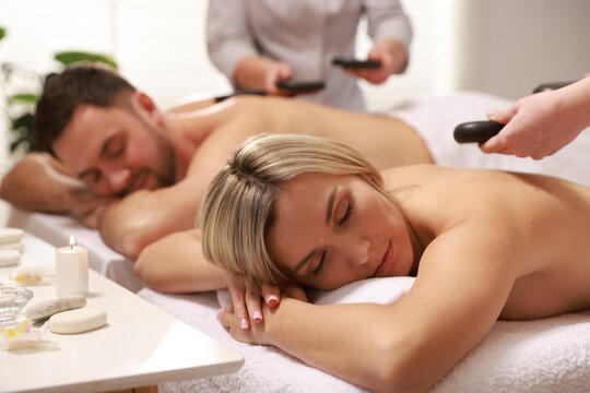 Couple receiving relaxing massage with stones in spa salon, selective focus