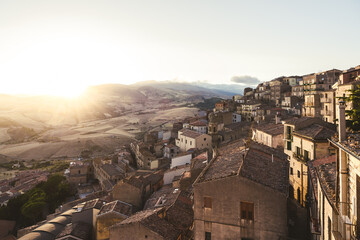 Obraz premium Terracotta rooftops overlooking rolling hills at sunset