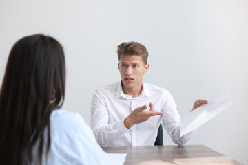 Obraz premium Young man complaining to woman at wooden table indoors