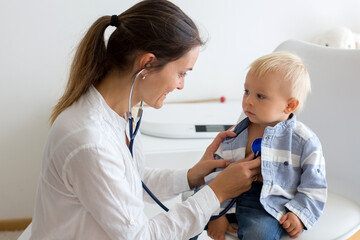 Pediatrician examining baby boy. Doctor using stethoscope to listen to kid