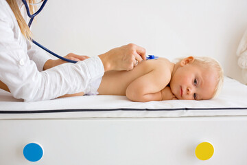 Pediatrician examining baby boy. Doctor using stethoscope to listen to kid
