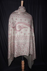 Elegant display of Kashmiri shawls draped on a mannequin, featuring intricate Sozni embroidery that...