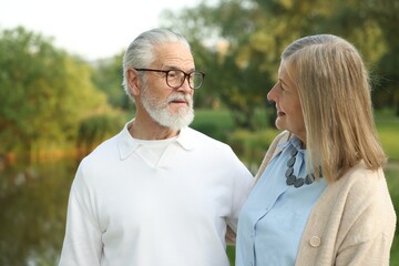 Lovely senior couple walking together near lake in park