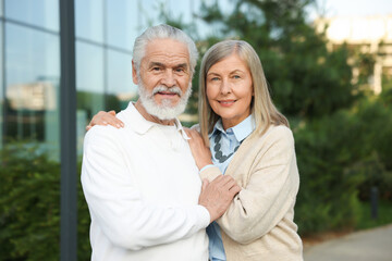 Lovely senior couple walking together near building outdoors
