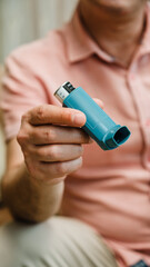Man Holding Blue Asthma Inhaler While Sitting Indoors in Casual Clothes