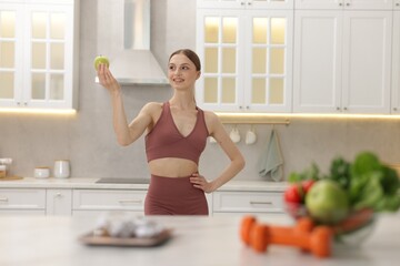 Slim woman with green apple in kitchen, selective focus