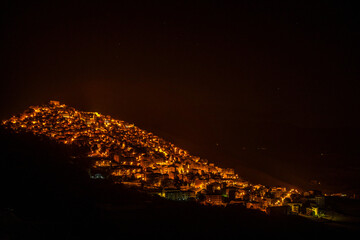 Hilltop village illuminated by warm lights at night