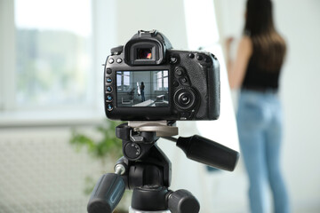 Woman near mirror in studio, focus on video camera recording her