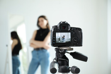Woman near mirror in studio, focus on video camera recording her