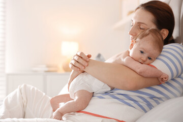 Mother putting her cute newborn baby to sleep at home