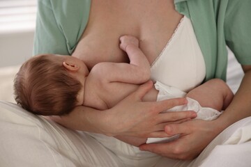 Mother breastfeeding her newborn baby indoors, closeup