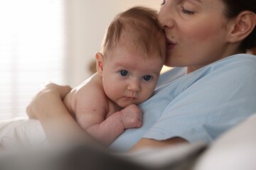 Mother putting her cute newborn baby to sleep at home, closeup