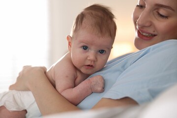 Mother putting her cute newborn baby to sleep at home, closeup