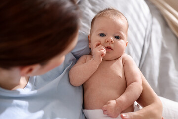 Mother putting her cute newborn baby to sleep on bed at home, above view