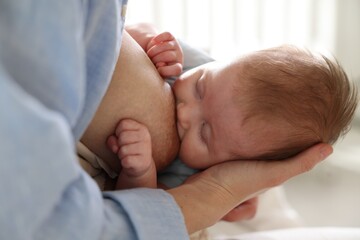 Mother breastfeeding her newborn baby indoors, closeup