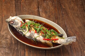 A Chinese Steamed Fish topped with Ginger and Shallots and seasonings, with hot oil poured over it to create a dramatic sizzle and an amazing sauce.
