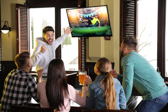 Football fans watching soccer match on TV set at bar