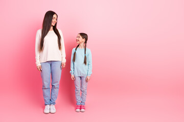 Mother and daughter bonding on a pink background showing connection and joy in casual attire for lifestyle themes