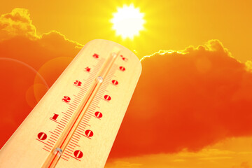 High temperature on thermometer against orange sky on sunny day. Hot summer weather