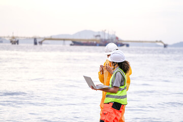 Two field scientists in PPE gear analyzing seawater samples using test tubes and a laptop. Environmental monitoring and pollution control on the coastline are depicted.