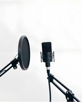 Professional black cardioid microphone mounted on adjustable boom arm with shock mount and round pop filter against clean white backdrop, ideal for podcasting and voice recording