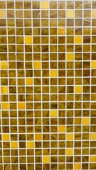 vertical photo of close up of yellow ochre and brown of a mosaic square tile wall as background