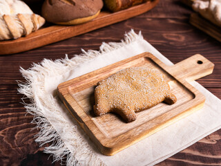 A traditional pig-shaped bread, adorned with sugar crystals, rest on a rustic wooden board
