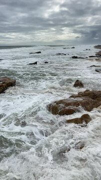Capela do Senhor da Pedra beach on sandy pinissula washed by winter cold Atlantic ocean waves on Praia do Senhor da Pedra in Nothern Portugal. Traveling, beauty in Nature concept slowmo vertical 4K