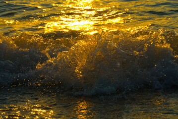 Golden sea surface splash with waves bubbles and shine summer water background