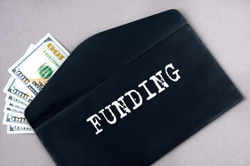 FUNDING - word on a black envelope with banknotes