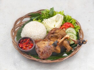 Nasi Bebek Goreng, fried duck served with rice chili sauce (sambal), tomato and cucumber.